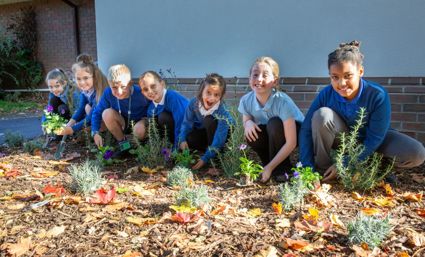 pupils are smiling and planting flowers 