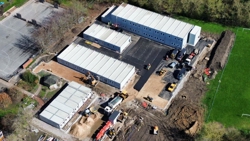 Aerial view of the school site to show how work is progressing with all four buildings in place, with several vehicles operating. 