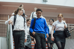 Secondary school pupils walking down a staircase inside their school.