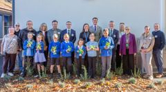 Pupils, councillors and partners are lined up, with the pupils holding wildflower plants 