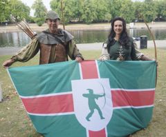 Actors playing Robin Hood and Lady Marian are holding the Notts Day flag 