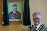 Councillor Roger Jackson stands in front of his portrait after his election as chairman in May 2022.