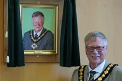 Councillor Roger Jackson stands in front of his portrait after his election as chairman in May 2022.