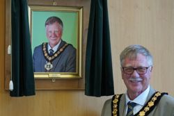 Councillor Roger Jackson stands in front of his portrait after his election as chairman in May 2022.