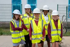 Pupils in hi-vis jackets are standing in front of the new building on the school grounds