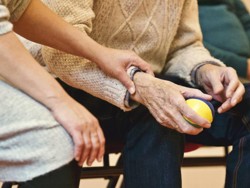 One person holding the arm of another who is holding a multi-coloured team.