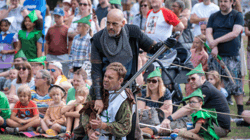 An action shot from a combat show from a previous event celebrating Notts Day. In the crowd are people wearing Robin Hood hats