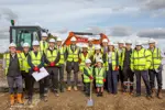 Councillor James Walker - Gerling and staff from Nottinghamshire County Council and Arc standing on the construction site of a new school with two children in front holding a spade. 