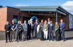 partners and teachers line up outside the new extended school building 