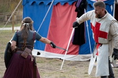 Two performers are both holding swords, locked in battle. 