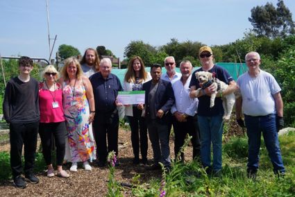 Councillors, volunteers at Jigsaw, are standing together in an allotment with councillors holding a giant cheque to demonstrate the amount of funding allocated 