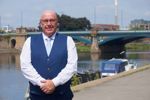 Cllr Mick Barton standing next to the River Trent, with Trent Bridge in view 