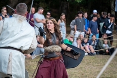 two performers are both holding up swords, locked in battle. 