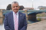 Cllr Bert Bingham standing outside County Hall with Trent Bridge in the background alongside river Trent 