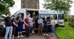 Volunteers, staff and members of the community are standing around the new minibus