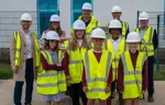 Councillors, partners and pupils of the school are all wearing hard hats and his vis jackets on the site of the new building which is under construction  