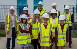 Councillors, partners and pupils of the school are all wearing hard hats and his vis jackets on the site of the new building which is under construction  