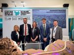 This shows a line up of local representatives, including from the county Council, standing in front of a sign which says Team East Midlands