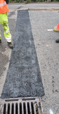 Photo shows an image of the same road, but after it has been repaired with a mastic boiler, The road surface looks smoother 