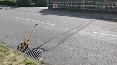 Example of a road before repairs. Picture shows a pothole next to a grate.