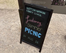 A black chalkboard with Fostering Summer Picnic written on it in colourful chalk.